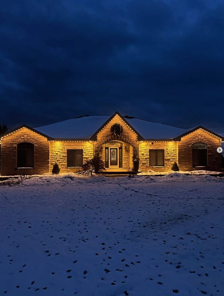 Bungalow in Simcoe County with warm-white permanent roofline lighting at dusk